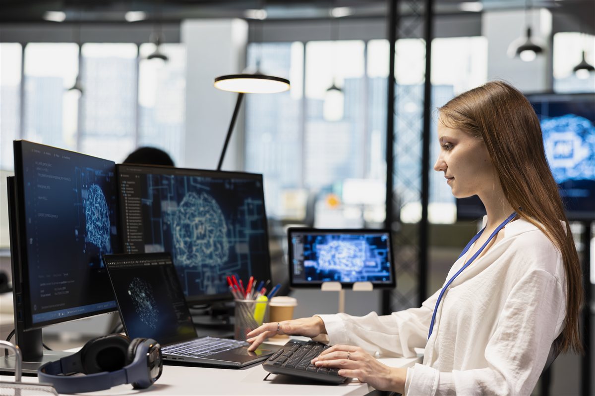 Colleague working at several screens in a modern office